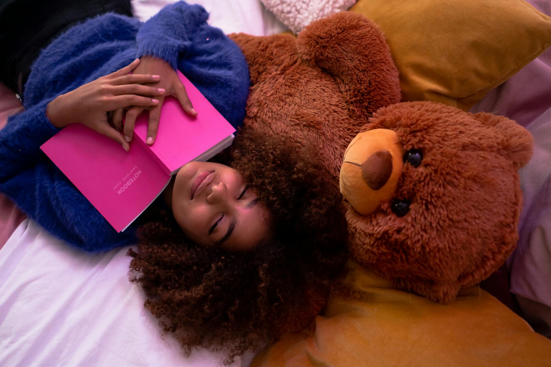 woman lying down on bed with her teddy bear