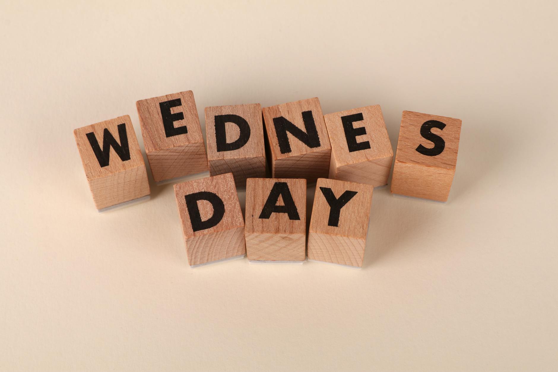 wooden blocks spelling wednesday on beige background